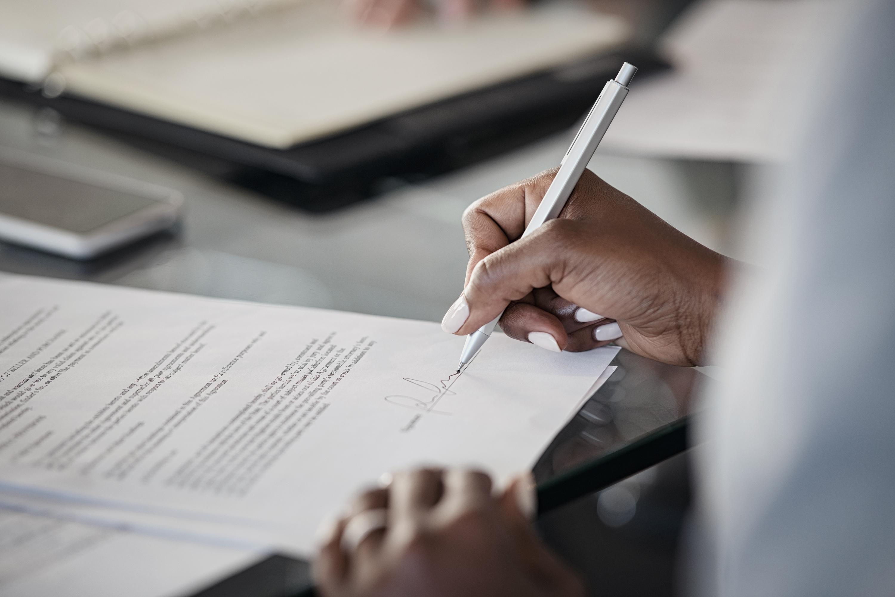 Close up of a woman's hand signing a document